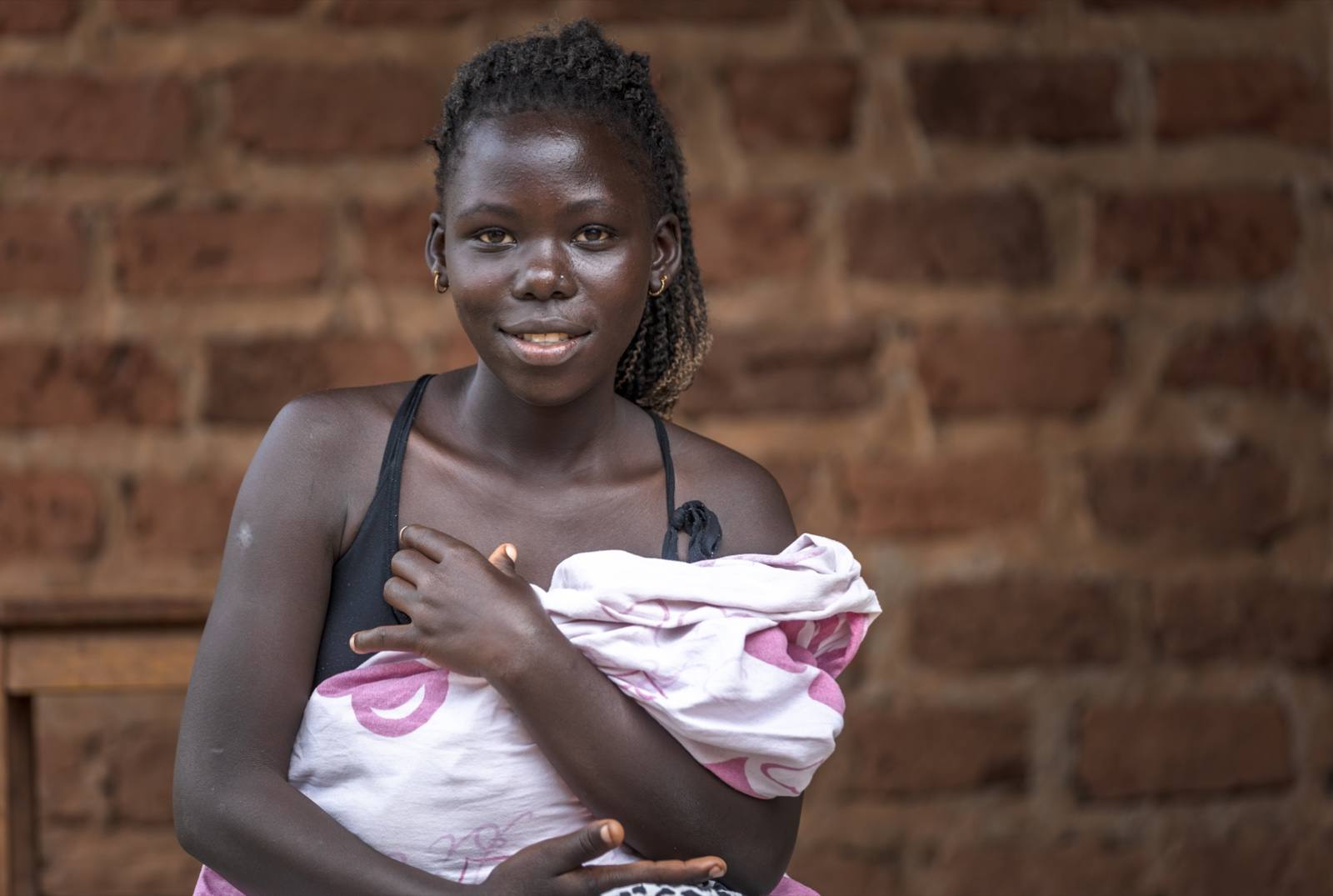 A mother holds her small and vulnerable newborn, swaddled after a Kangaroo Mother Care home visit